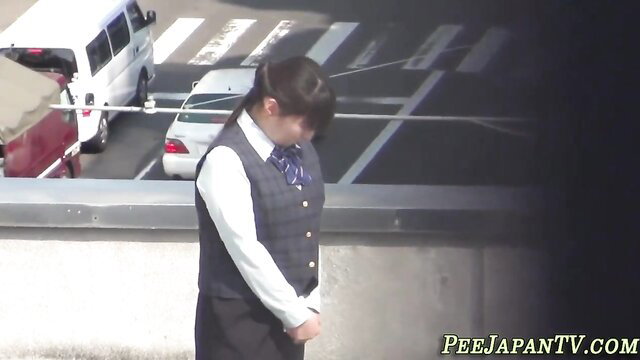 Japanese schoolgirl in uniform peeing outdoors on parking garage