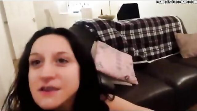 Dark haired tattooed woman closeup face smirking on couch