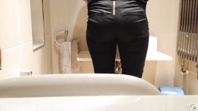 Hot brunette in tight black pants bends over in bathroom