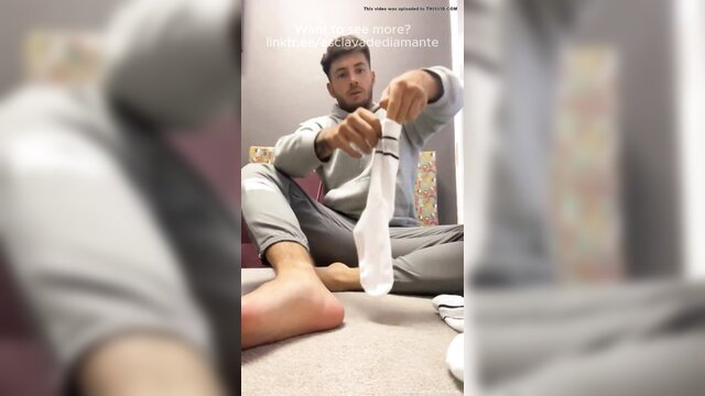 Hot guy holding sweaty white socks with bare feet, sock fetish tease