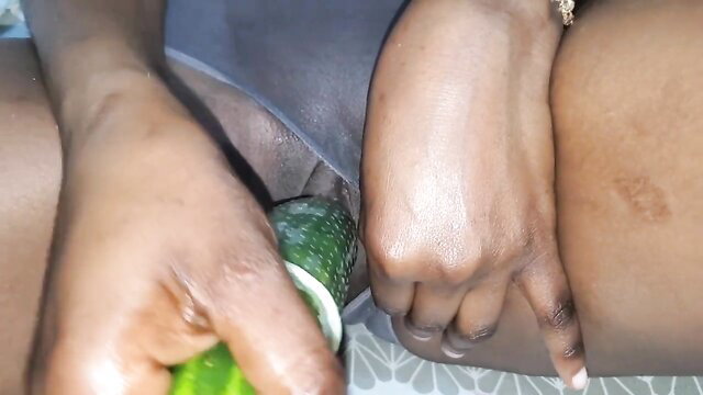 Black woman grips huge green cucumber near man's big black cock