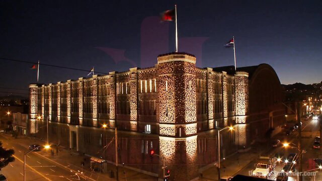 Lit Alcatraz prison at night, stunning architecture with flags