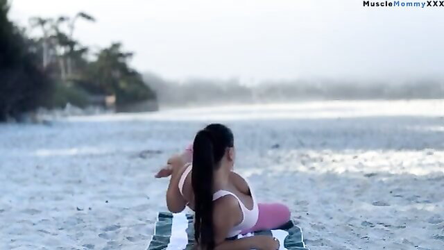 BiancaData Muscly Asian mom deep stretching in pink yoga gear on beach