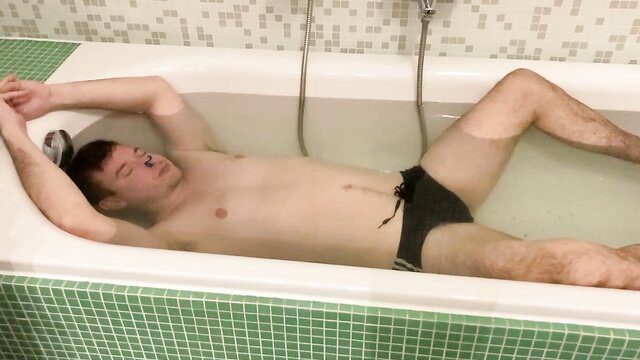 Hot guy in black speedo relaxes asleep in bathtub, breathhold tease