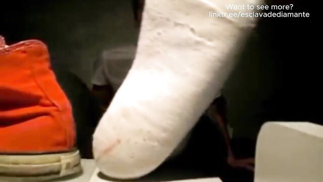 Youngster's smelly white socks and bare foot next to red Converse sneaker