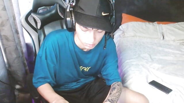 Young tattooed twink in headset sits on gaming chair, gay amateur tease