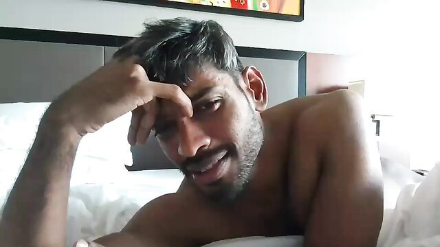 Sexy shirtless Indian man with beard lounging nude on bed