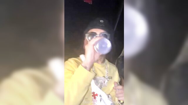 Mystery model sips from bottle at nightclub in yellow jacket and shades