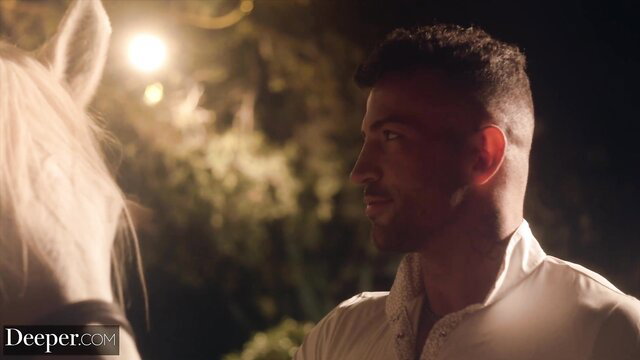 Handsome muscular man in white shirt with horse in dark erotic night scene