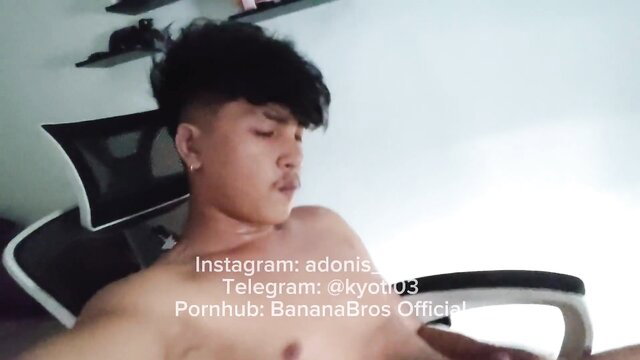 Shirtless Asian twink with undercut hair lounges nude in chair