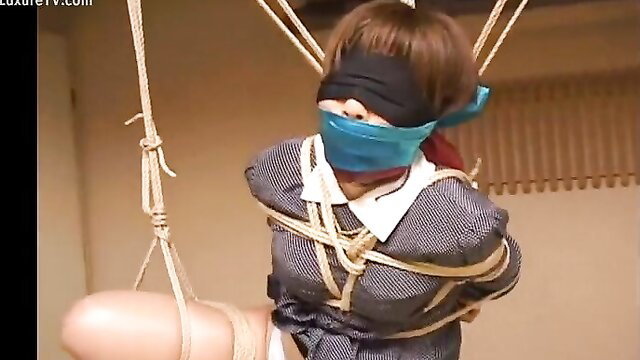 Bound Asian woman in schoolgirl outfit gagged and suspended in ropes