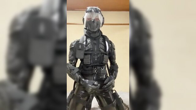 Male in shiny black rubber tactical gear and helmet posing seductively
