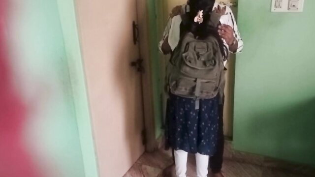 Indian college girl in skirt and backpack stands in doorway after class