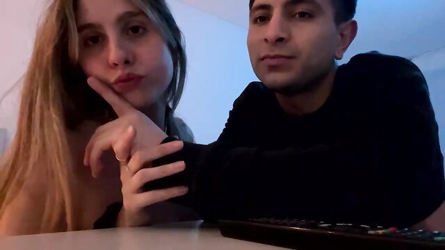 Blonde cutie teases with finger on lips next to brunette guy on cam