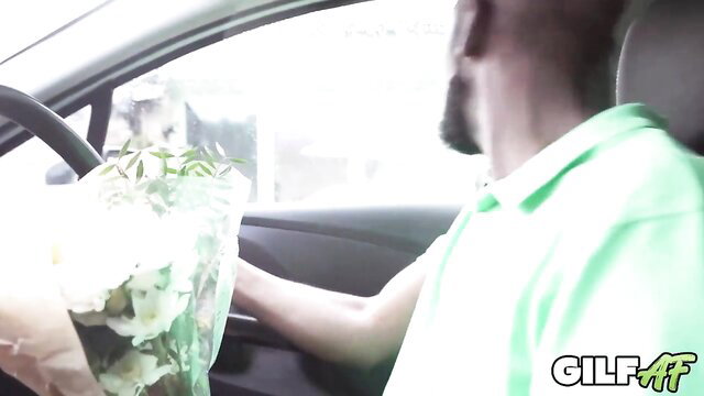 Ebony guy in car holds flowers, GILF logo on mature plumper vid thumbnail
