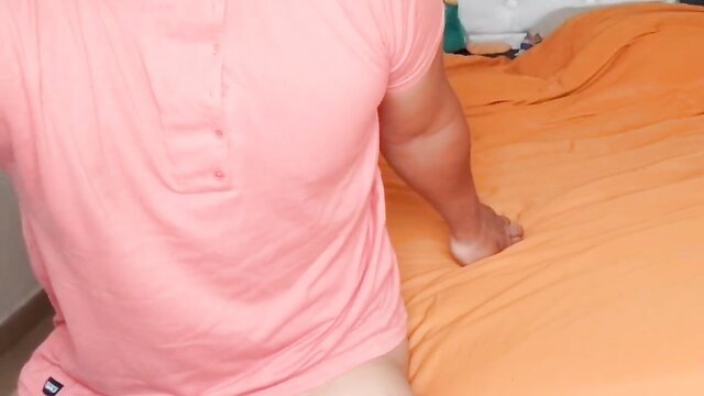 Latino man masturbating on orange bed in pink shirt