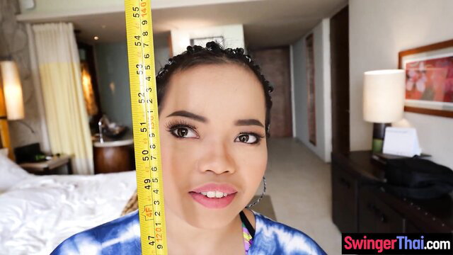 Super tiny Thai teen with ruler measuring petite face in hotel