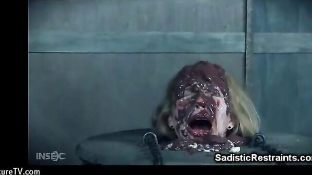 Blonde woman gagged, restrained, covered in fluids in BDSM scene