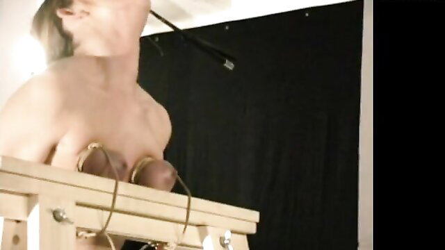 Nude woman bound with rope around big tits on wooden frame