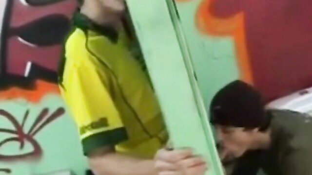 Two athletic men in yellow soccer jerseys engage in gay outdoor sex against graffiti wall