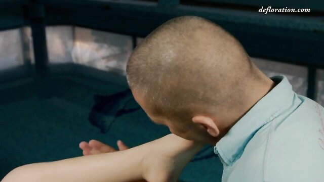 Bald man kissing woman's arm in poolside erotic scene