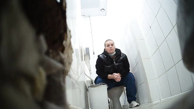 Spy cam of shaved-head woman squatting on toilet in shopping center bathroom