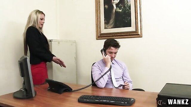 Blonde in red skirt stands over suited guy on phone at desk in Wankz scene