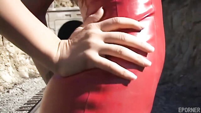 Amber Jayne in shiny red latex dress, teasing curves outdoors