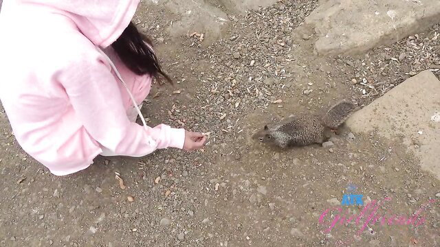 Summer Renee in pink hoodie feeding squirrel outdoors