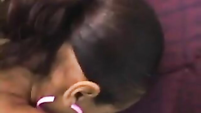 Closeup of black woman's ear with pink earrings on purple bedding