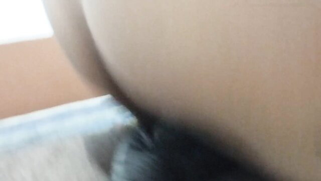 Blurry closeup of woman's pale round ass in black thong pulled aside