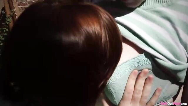 Redhead in green lace bra pressed against man's hand in intimate match scene