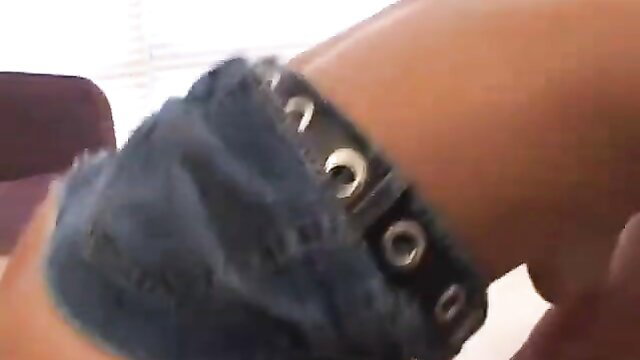Cute woman's arm in frayed denim skirt with studded bracelet closeup