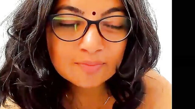 Closeup of sexy Indian woman's face with bindi and glasses, soft smile