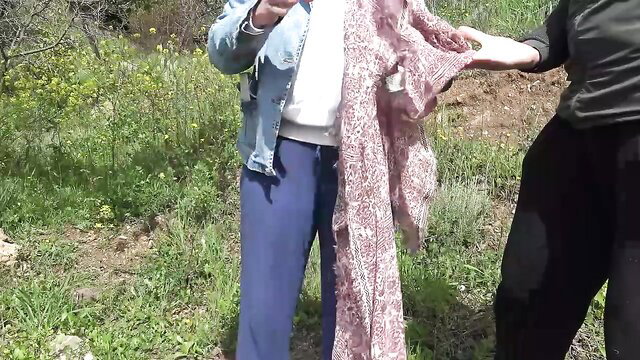 Souzan Halabi in denim jacket and pants holding pink scarf outdoors