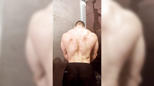 Hot muscle dude flexing ripped back in gym shorts