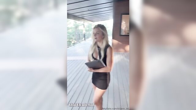 Trippie Bri in tight black dress on balcony holding tablet
