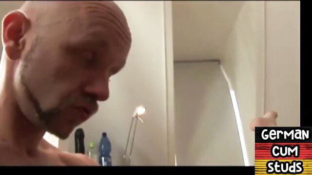 Bald man with facial hair and tattoos looking down, possibly after sex