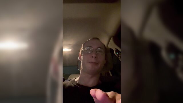 Glasses guy in car smirks at camera, finger extended teasingly in JOI tease