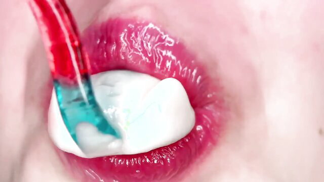 Closeup of woman with glossy pink lips sucking red and green candy cane with white cream