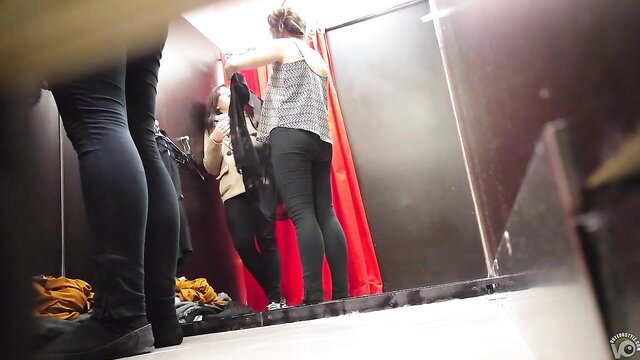 Cute brunette tries on clothes in store fitting room, tight jeans
