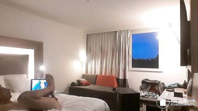 Slim Asian guy lying nude on hotel bed, legs up, laptop on lap