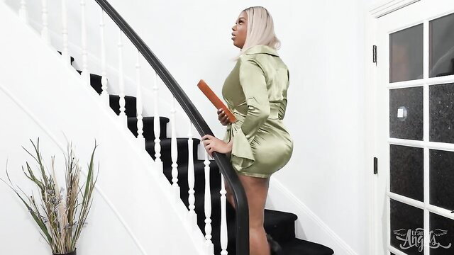 Busty blonde shemale in tight green satin dress on stairs