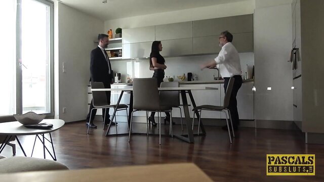 Barbara Bieber in tight black dress with two suited men in kitchen threesome