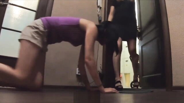 Mistress in black dress with feet near kneeling slave girl