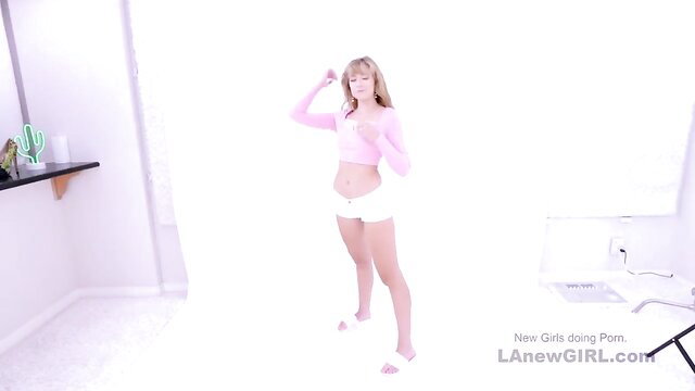 Beautiful blonde teases in pink top and white shorts in studio