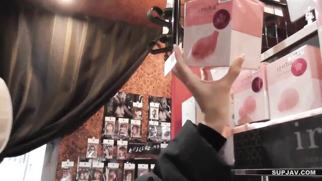 Woman in sex shop holding pink onahole fleshlight toy from shelf