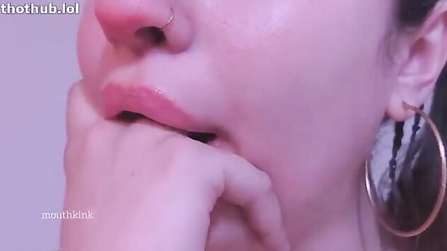 Closeup of woman's glossy lips and open mouth with hand, mouth kink tease