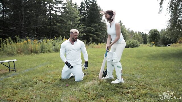 Emma Rose in white cricket outfit kneels for outdoor trans passion