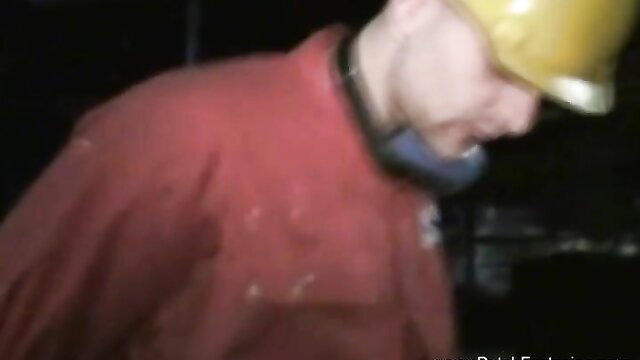 Construction worker in hard hat and collar in dimly lit adult scene